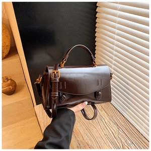 Close-up of dark brown vintage faux leather handbag showing glossy texture and gold hardware