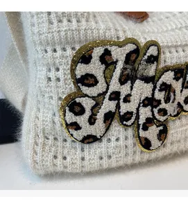 Close-up of knit texture with leopard chenille patch and gold glitter edges