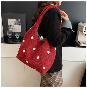 Detail of red plush tote bag with white heart patterns and secure metal snap closure