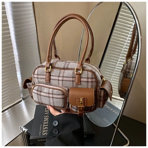 Détail d'un sac à main en tweed à carreaux gris avec finitions en cuir marron et doré