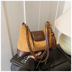 Détail du sac en daim matelassé marron avec chaîne dorée et gland décoratif à franges