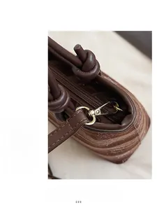 Détail du sac seau imprimé marron avec poignée en cuir nouée et fermeture éclair dorée