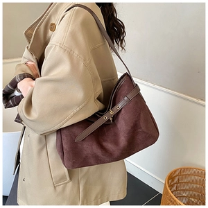Close-up of a deep brown suede patchwork shoulder bag worn with a beige trench coat