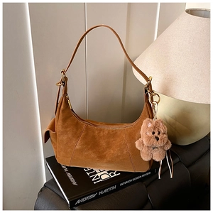 Brown suede hobo shoulder bag featuring a cute plush bear charm on a stack of books