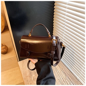 Detailed macro view of dark brown PU leather texture and metallic strap buckle on handbag