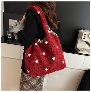 Detail of red plush tote bag with white heart pattern and wide shoulder strap