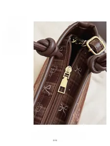 Gros plan sur la fermeture éclair et le motif ours du sac seau marron chic