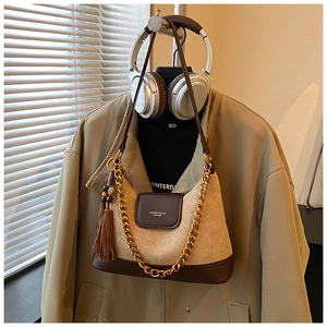 Détail du sac matelassé en suédine avec chaîne dorée et gland à franges marron