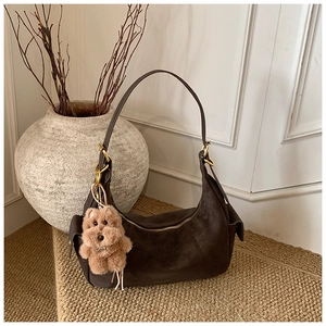 Detail of dark brown suede hobo bag with gold hardware and plush puppy charm
