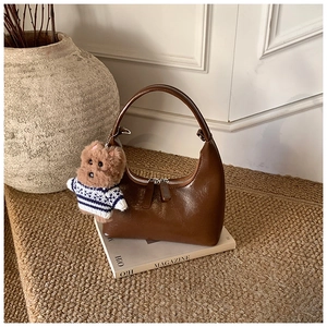 Détail du sac hobo en cuir marron foncé avec un joli charme de chiot en peluche