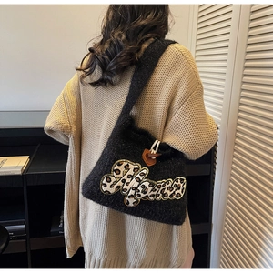 Detail of black knit tote bag with Alana leopard patch and toggle button on shoulder