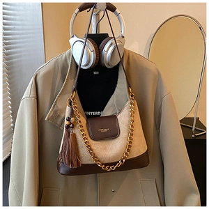 Détail du sac vintage en daim matelassé avec chaîne en métal et gland en cuir brun
