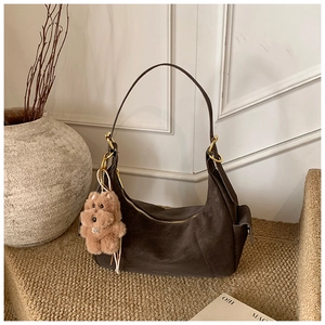 Detail of dark brown half-moon hobo bag with gold hardware and plush dog charm