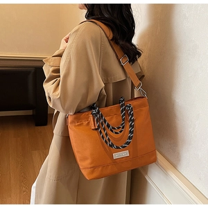 Détail du sac cabas en toile orange avec poignées en corde tissée et bandoulière large