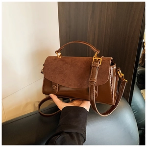 Detail of vintage brown handbag featuring spliced matte suede and smooth leather texture