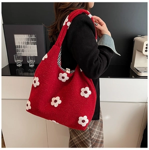 Detail showing red fleece tote bag with white floral pattern and spacious plaid interior