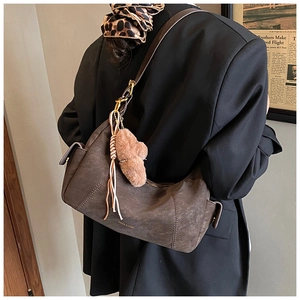 Detail of vintage brown crossbody bag with matte texture and cute plush bear charm accessory