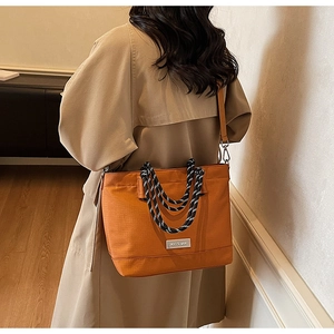 Détail du sac cabas orange en oxford avec poignées tressées et plaque de marque