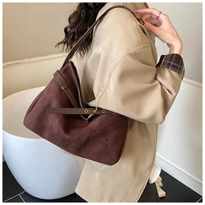 Detail of dark brown suede shoulder bag with leather strap and gold metal hardware