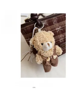 Gros plan d'un ours en peluche avec salopette en velours sur un sac à carreaux marron