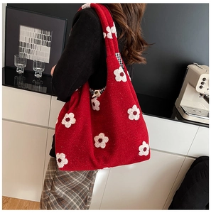 Close-up of red plush tote bag featuring white floral patterns and checkered lining