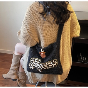 Detail of black knit tote bag with leopard print HAPPY patch and wooden toggle button