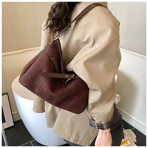 Detail of dark brown suede tote bag with adjustable leather strap and gold metal buckle