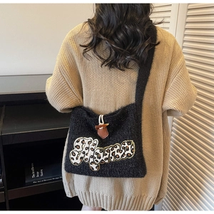 Detail of black knit crossbody bag with leopard print patch and toggle button