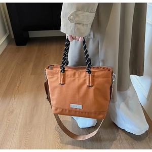 Détail du sac cabas oxford orange-brun avec poignées tissées et large bandoulière en tissu