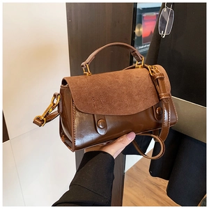 Detail of brown vintage crossbody bag featuring suede patchwork and gold metal hardware