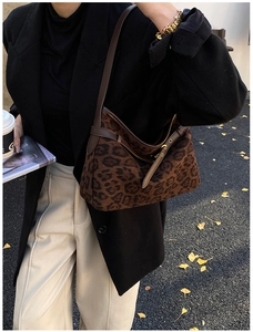 Detailed close-up of leopard print faux suede hobo bag with brown leather strap and buckle