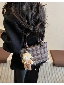 Detail of brown plaid bucket bag with bow prints and a plush teddy bear charm