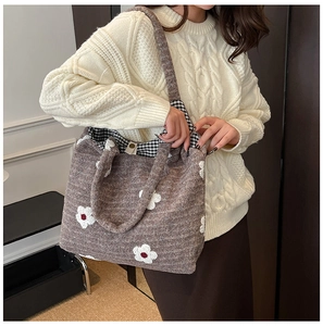 Detail of a brown knitted tote bag with white daisy patterns and black-white checkered lining