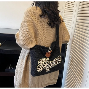 Detail of knitted shoulder bag featuring leopard Mama patch and horn buckle closure