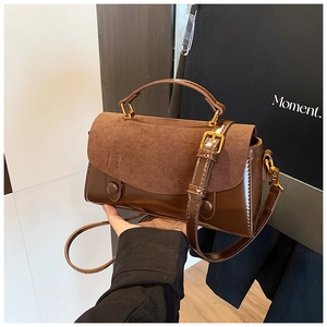 Detail of vintage brown handbag featuring matte suede and glossy patent leather contrast