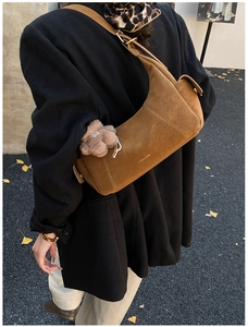 Brown suede hobo bag with teddy charm detail on a model in a black winter coat