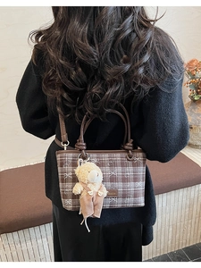 Detail of a brown plaid bucket bag with bear patterns and plush bear charm decoration