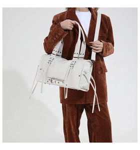 Detailed view of white motorcycle tote bag with studs and tassels on a corduroy blazer