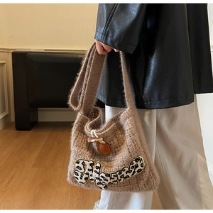 Close-up of brown knit shoulder bag with leopard letter detail and horn button closure