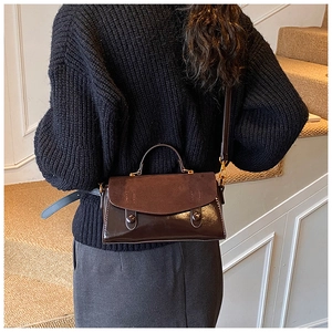Macro shot of dark brown mixed-texture flap bag on model with black sweater