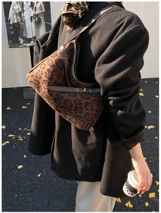Chic leopard print underarm bag with gold buckles styled on a black blazer