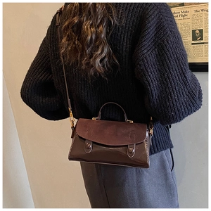 Deep brown patchwork shoulder bag with suede flap and gold hardware in life-style setting