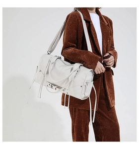 Detailed view of a white PU leather tote with tassels and detachable strap on a model