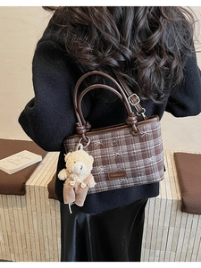 Détail d'un sac à main marron à carreaux avec breloque d'ours en peluche et logo