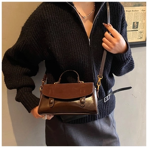Close-up of brown vintage leather crossbody bag with mixed suede and gold hardware