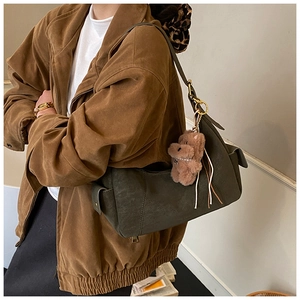 Detail of dark green suede hobo bag with a cute brown plush dog charm on a model
