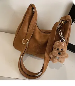 Dettaglio borsa in pelle PU marrone motivo litchi con tracolla e ciondolo a cane