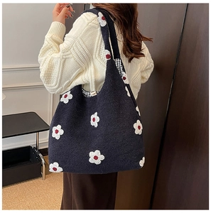 Detail shot of navy blue knit tote bag featuring white floral patterns with red accents