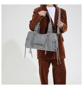 Detailed view of the gray distressed leather tote with long fringe and vintage metal buckles