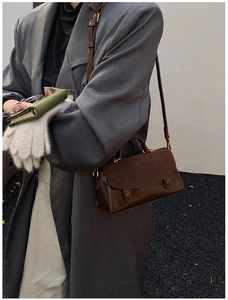 Detail view of dark brown leather crossbody bag with suede flap on model in grey coat